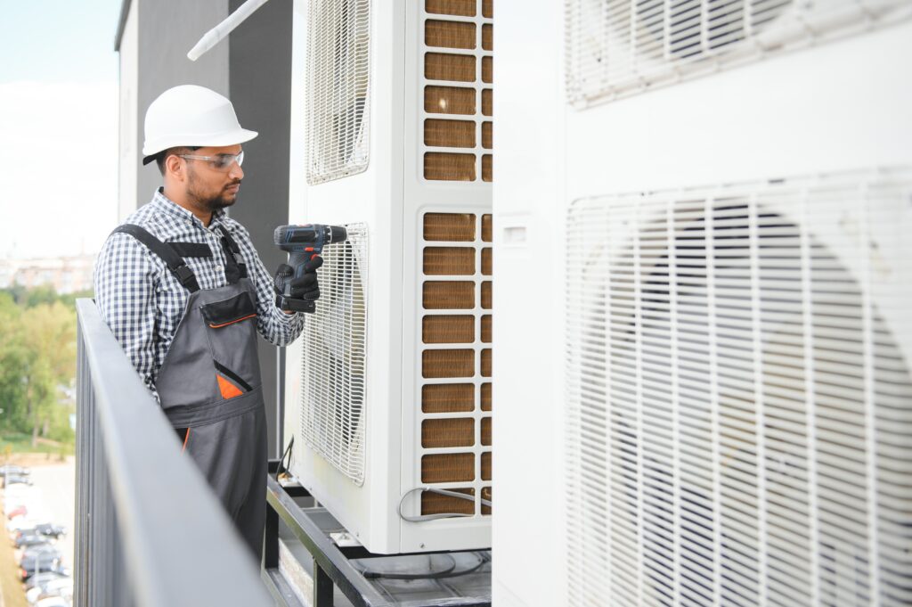 Repairman in uniform installing the outside unit of air conditioner